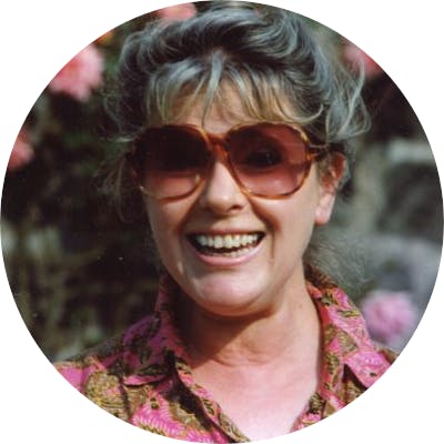 Portrait of Suzanne Rappaport Ripton smiling in a pink patterned blouse.