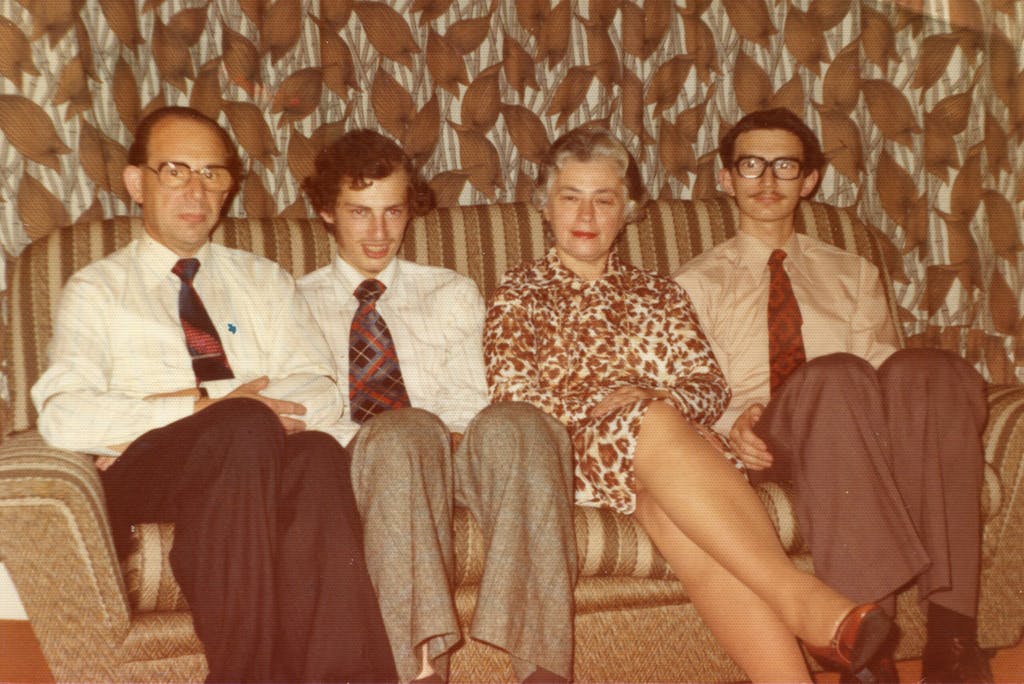 Zygi and Berta with sons Richard and Philip, seated on a stripy sofa against patterned curtains.